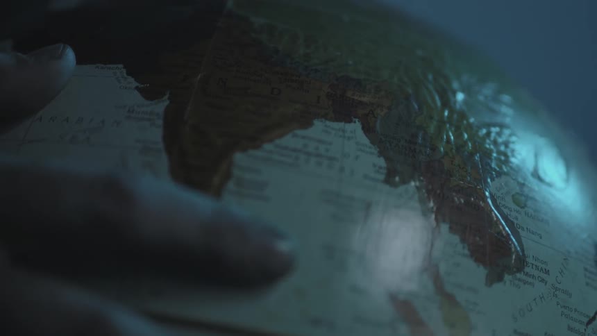 A hand pulls a globe backwards