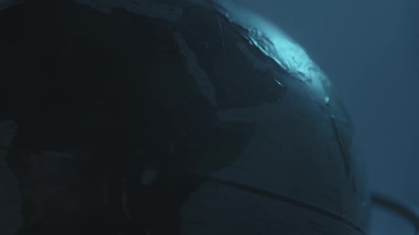 A world globe sits still in a dark area