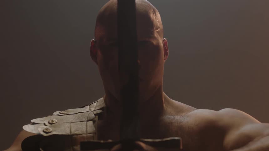 A warrior is raising his sword in front of himself with both hands