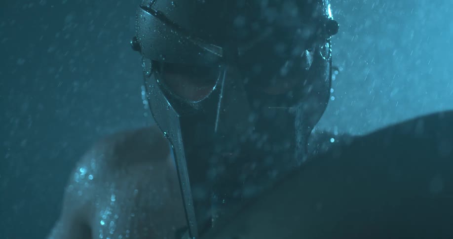 Rain is falling on a warrior wearing a helmet