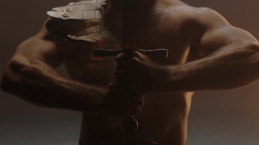 A man lowers a sword held in front of his face