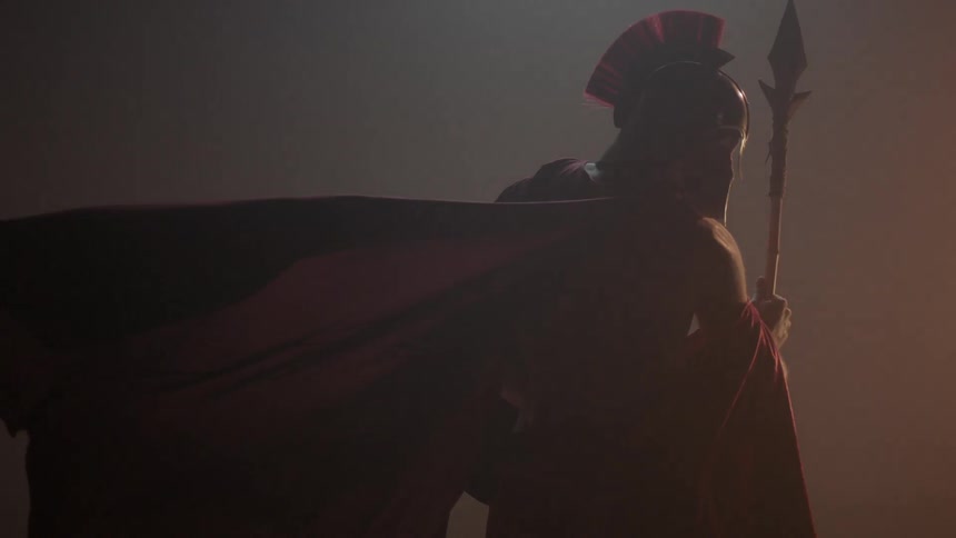 Man wearing a red cape and helmet holds a spear