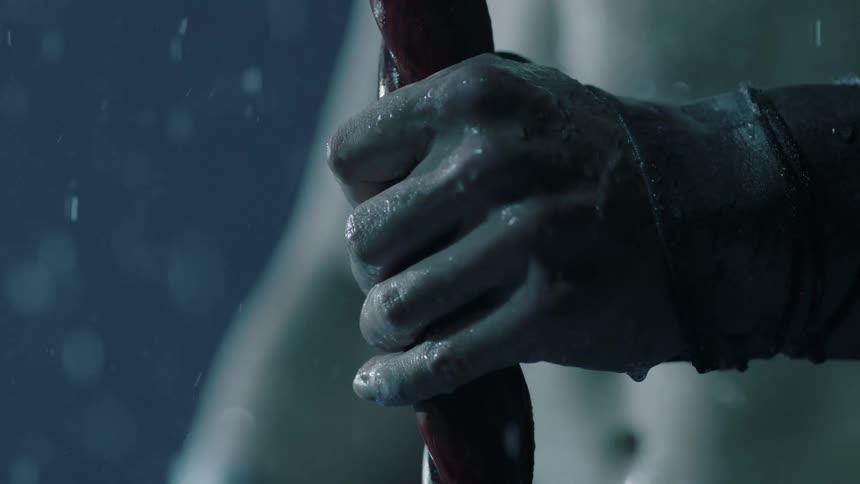 A person standing in the rain grips a wooden staff