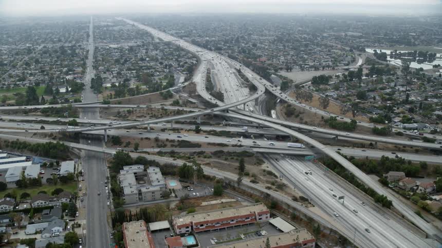 An epic aerial shot of the Interstate 5 and Highway 118 interchange in Mission Hills CA during daylight hours with light traffic and surrounding city infrastructure