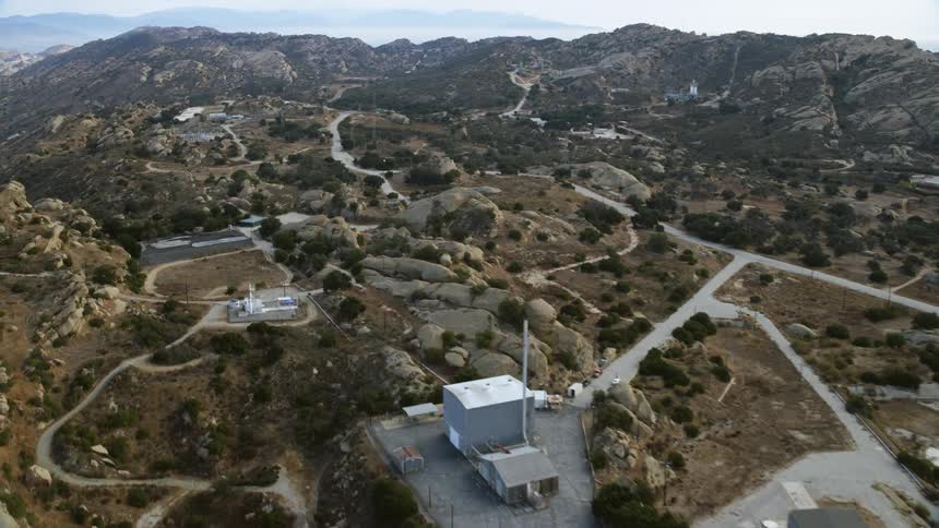 Aerial footage flying over and orbiting Rocketdyne aerospace testing facility in Brandeis California featuring the network of roads connecting facilities scattered among hills and mountains