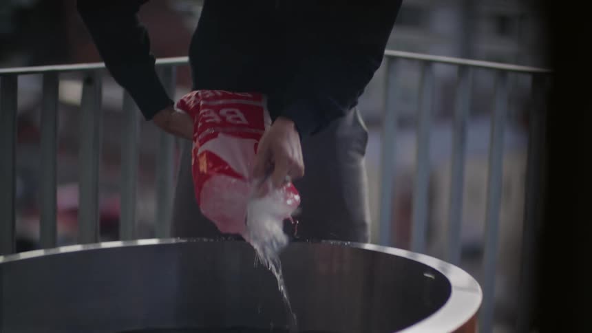 A man seen pouring ice from a plastic container into a big bowl