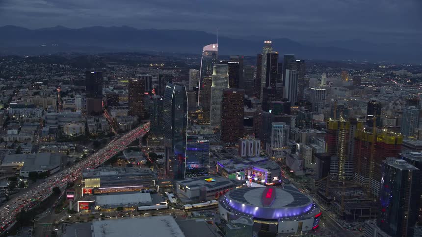 Aerial footage orbiting downtown LA skyscrapers the Staple Center and Interstate 110 at twilight
