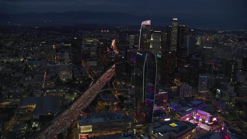 Aerial footage of heavy traffic at twilight with downtown Los Angeles skyscrapers and Staples Center in view