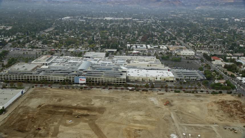 This is an aerial shot of the Westfield Topanga Mall in Woodland Hills California with cloudy skies and shotover F1 cinematography captured during daytime in southern Californias spring or summer season