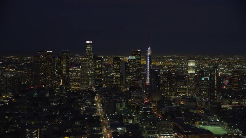 A breathtaking aerial view of Los Angeles downtown area at night showcasing spectacularly lit skyscrapers against the clear starry California skies