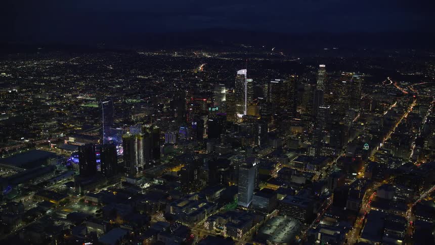 A stunning shot of the Southern California cityscape featuring brightly-lit skyscrapers and superstructures against a clear night sky