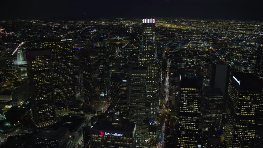 Approaching US Bank Tower at night this aerial stock footage showcases the glowing high rise buildings and skyscrapers of Downtown Los Angeles California