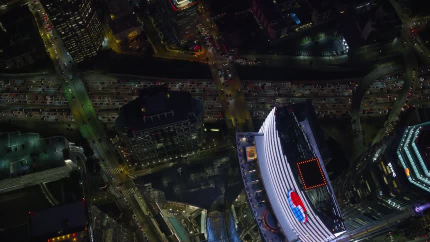 An aerial shot of the Wilshire Grand Center and heavy traffic on the 110 Freeway in Downtown LA during nighttime rush hour