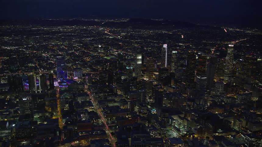 Stunning aerial footage showcasing the brightly lit-up downtown skyline of Los Angeles California during summer nights