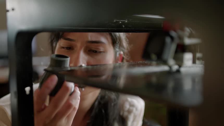 A woman watches closely as a 3d printer creates an object