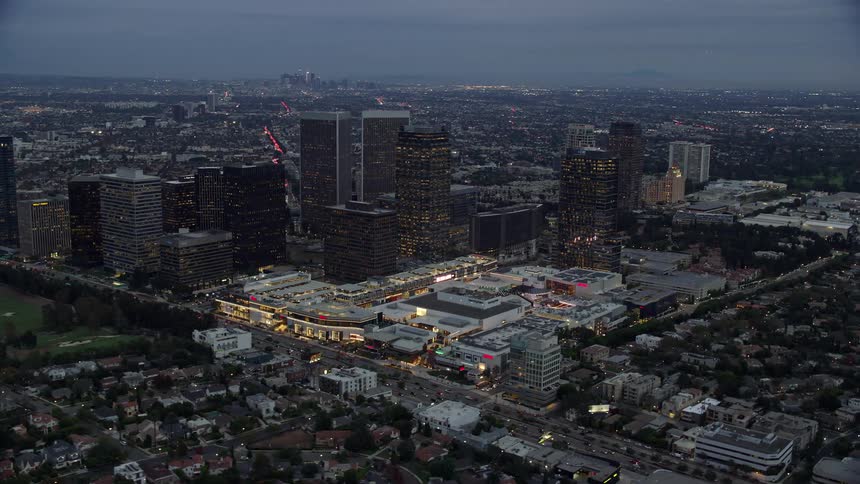 Aerial footage orbiting Westfield shopping mall and office buildings during twilight in Century City California