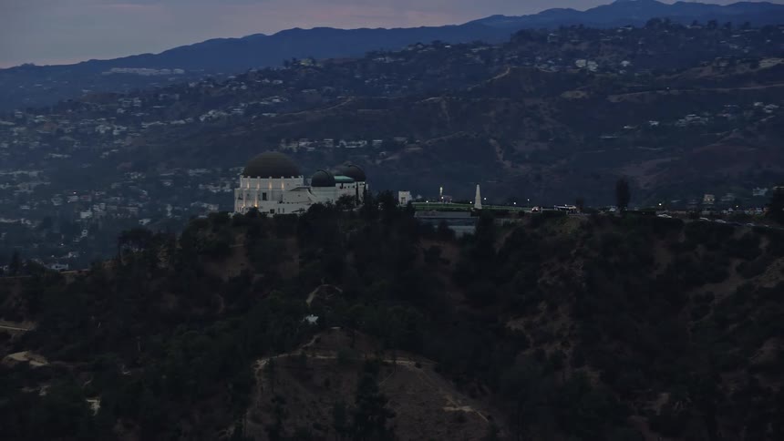  aerial footage of Griffith Observatory during twilight against the Hollywood hills in Los Angeles California