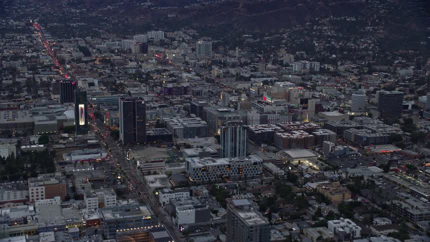 An epic aerial shot showcasing businesses and landmarks along Hollywoods famous Sunset Boulevard at twilight in California