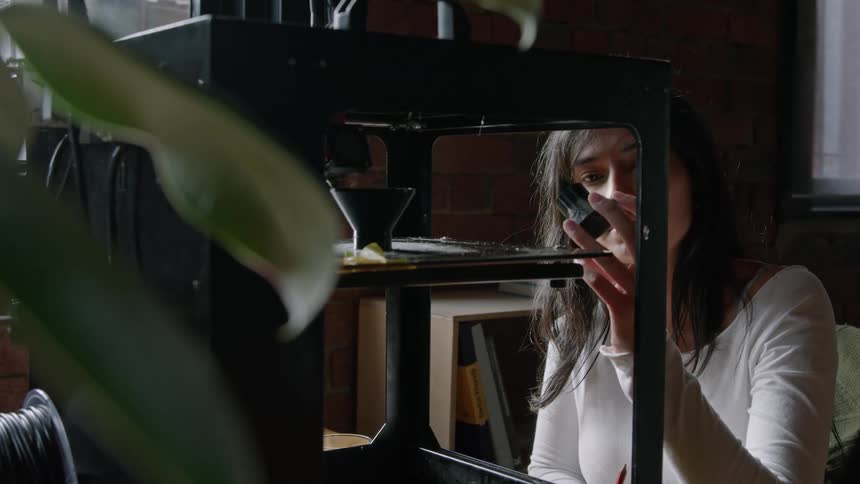 A woman watches the 3d printer work