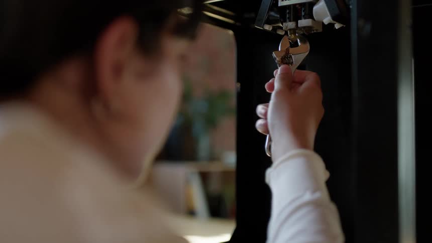 A woman is holding a wrench as she turns a bolt inside a machine