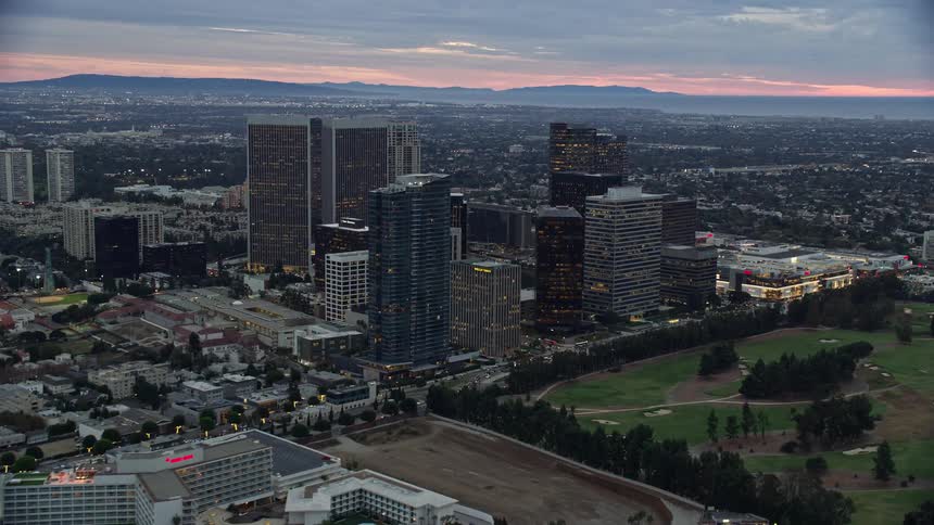 A breathtaking aerial view of Century City California during twilight flying past iconic hotels Waldorf Astoria and Beverly Hilton toward the citys impressive office buildings