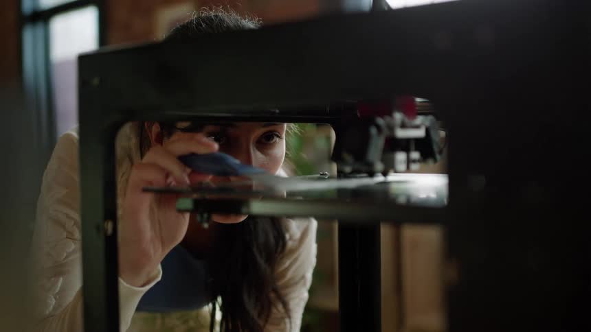A woman is cleaning the 3d printer