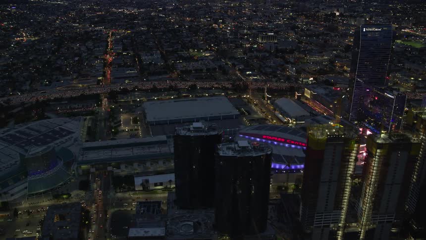 An epic aerial orbiting around Oceanwide Plaza at twilight featuring the iconic Staples Center and downtown LAs skyscrapers in Southern California