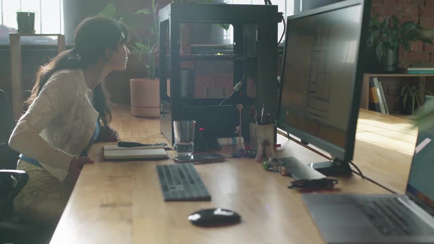 A woman is sitting at her computer desk and typing