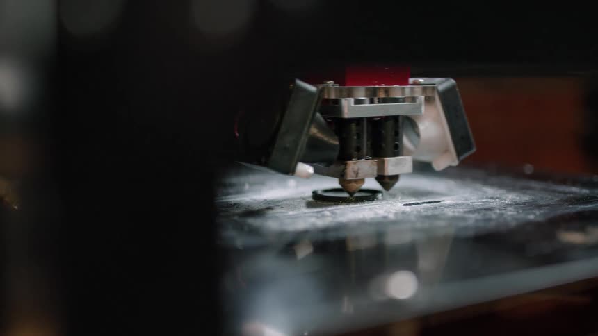 A three dimensional printer moves around and object it is creating