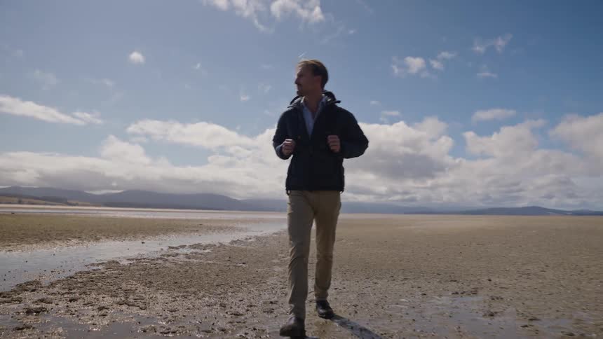 A man is hiking outdoors through a desert area