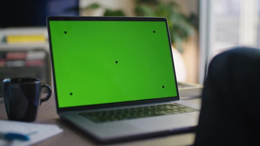 Office worker sits at desk with laptop and mug