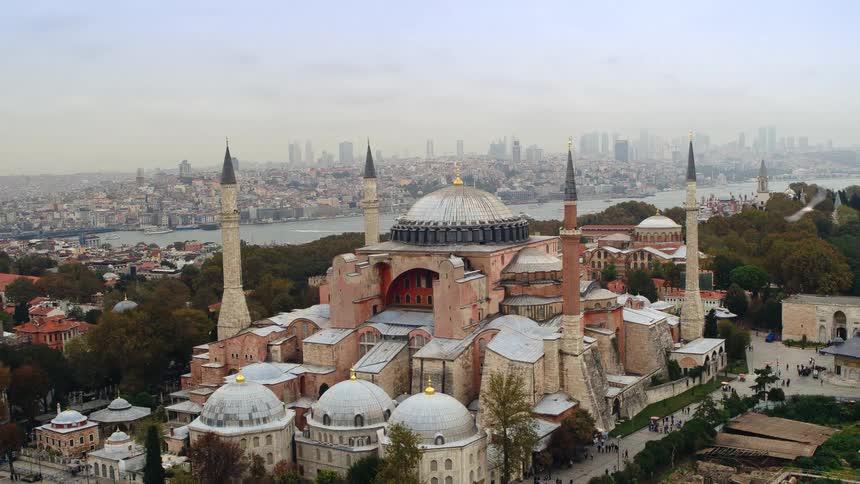 A mosque sits along a river across from downtown