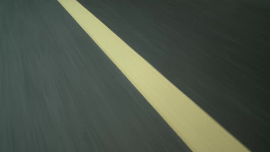 A close up of a yellow strip of paint on a paved road