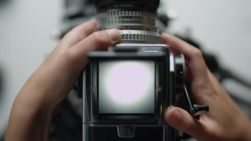 A persons hands using a camera reel making the camera screen turn white