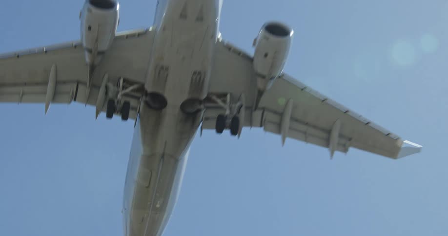 A plane flying overhead and relatively close to the ground close enough to see the underside of the plane