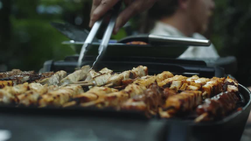 People are sitting outdoors and grilling food