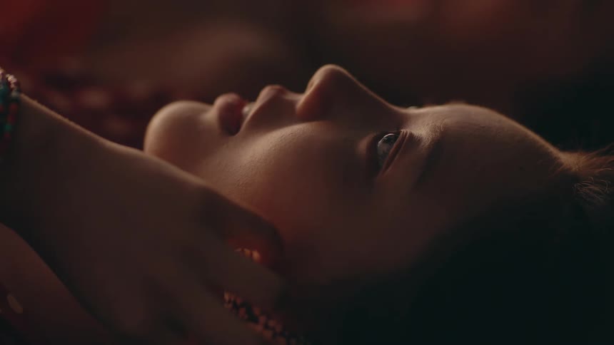 A close up of a womans face as she puts her hand up to her cheek while looking up at the sky