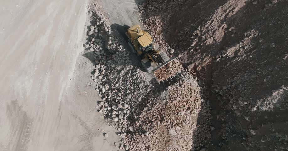 A truck is moving dirt and gravel along the side of a cliff