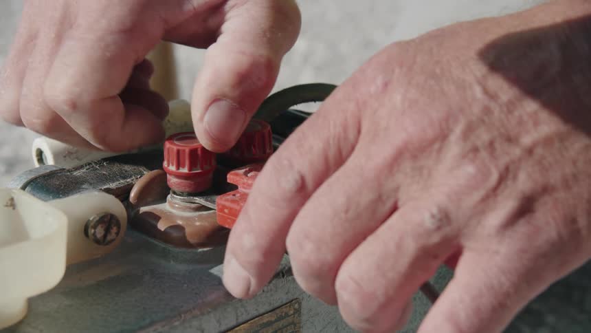 A close up of a mans hand twisting a dial on a device