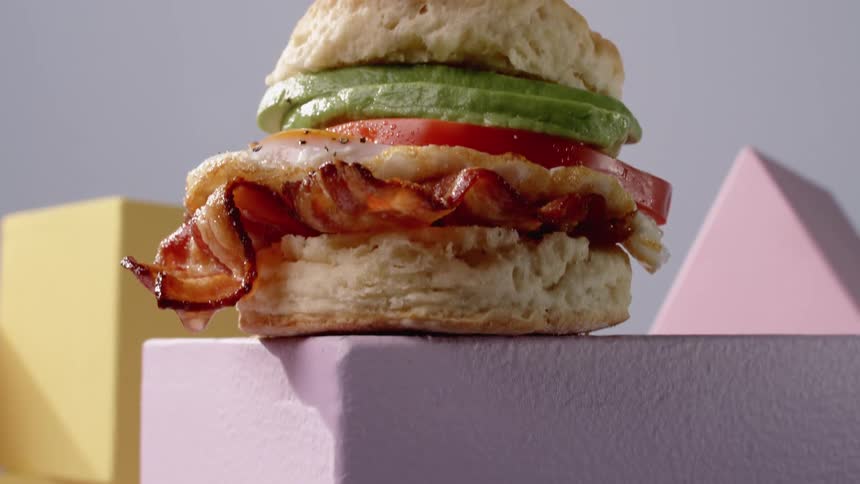 Bacon chicken club sandwich on a biscuit with tomato and avocado on a pedestal