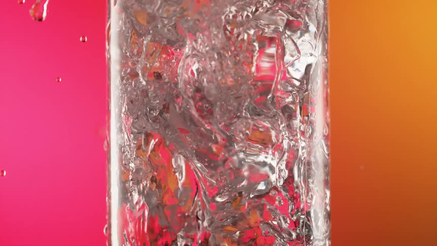 Slow motion of liquid being poured into a glass is displayed