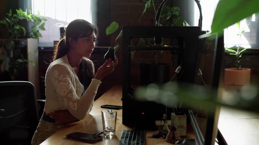 Woman with ponytail white shirt and brown pants sit at desk in the office