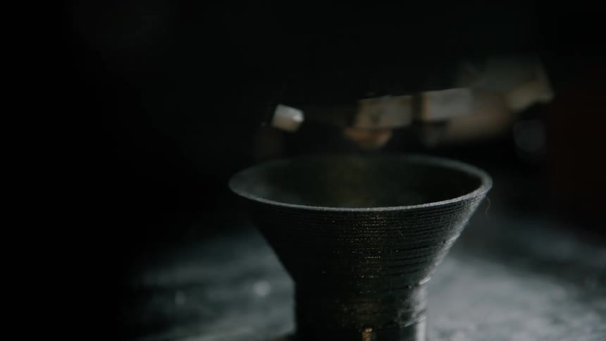 The probe of a 3d printer moves around as it creates a funnel shaped object