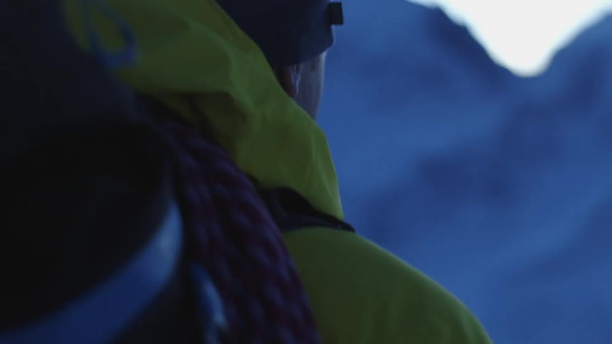 Back of the head of a man carrying a backpack while hiking on the mountains at morning