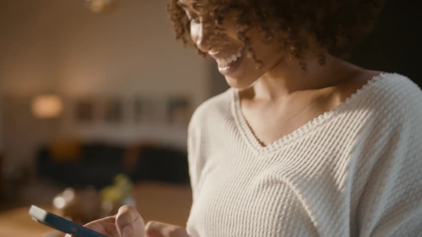 A woman laughs while texting on her smartphone