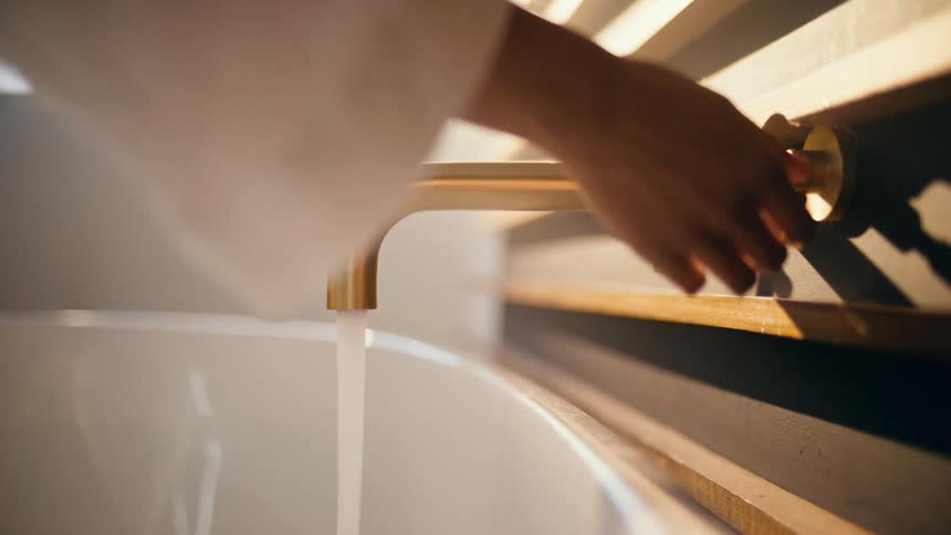 A woman turns on a faucet to run a bath
