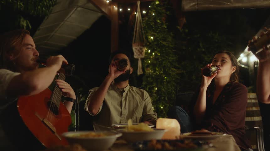 A group of friends gathered around a table filled with drinks and delicious food