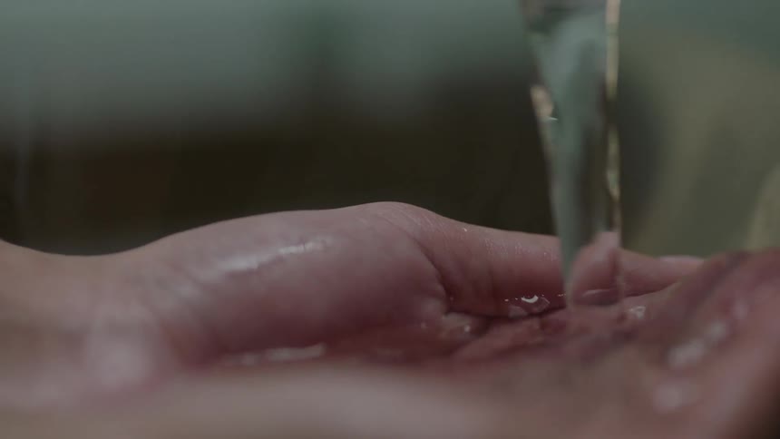 A person holds their hands under the water