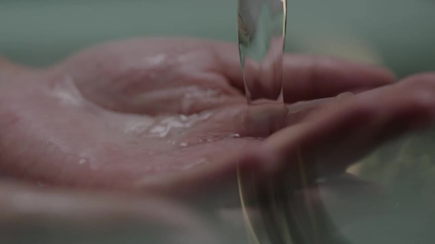 Water slowly runs over a person's hands