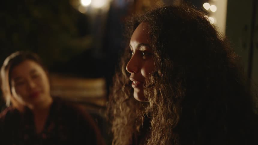 Close up of the face of a young woman talking to friends in a cozy room